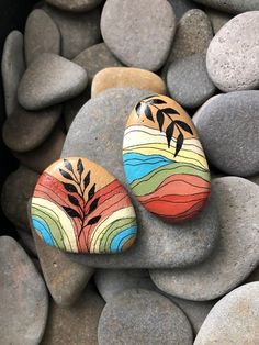 two painted rocks sitting on top of some rocks