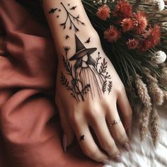 a woman's hand with a black and white tattoo design on it, next to flowers