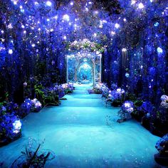 an outdoor garden with blue flowers and lights on the walkway, surrounded by greenery