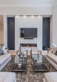 a living room with couches, tables and a flat screen tv mounted on the wall