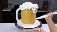 a person is cutting into a cake with a beer mug on the top and marshmallows on the bottom