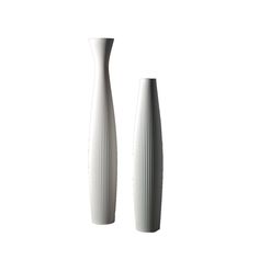 two tall white vases sitting next to each other on a white surface with no one around them