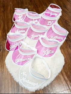 a pile of pink and white personalized baby bibs sitting on top of a wooden floor