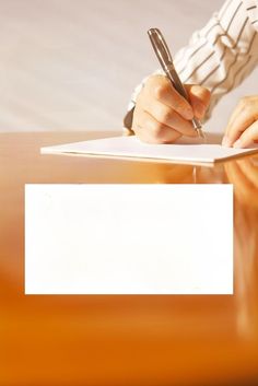 a person writing on a piece of paper with a pen in their left hand and a white sheet of paper behind them