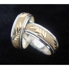 two gold wedding bands with leaves on each side, set against a black velvet background