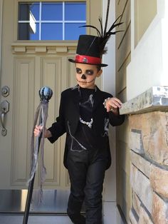 a young boy dressed up as a skeleton with a top hat and feathered tail