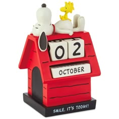 a snoopy doghouse clock with two dogs on it's roof and the date is