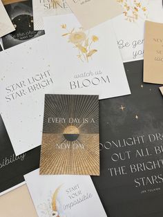 many different types of greeting cards are on the table with gold foil and black paper