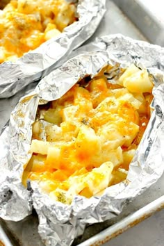 two foil packets filled with food sitting on top of a pan