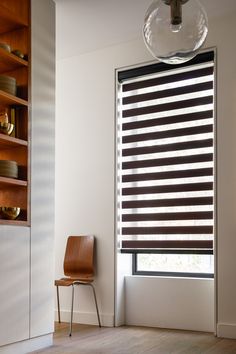 a chair sitting next to a window covered in blinds