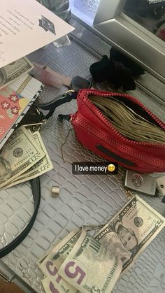 a red purse sitting on top of a table covered in money