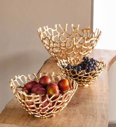 two bowls filled with fruit sitting on top of a wooden table