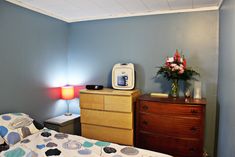 a bed room with a neatly made bed next to a night stand and a dresser