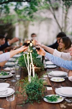 a group of people sitting at a table toasting with wine glasses