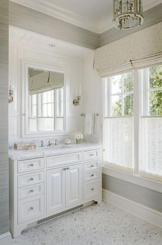 a white bathroom with double sinks and large windows