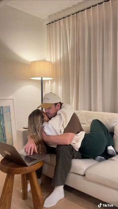 a man and woman kissing while sitting on a couch in front of a laptop computer