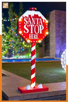 a red and white stop sign sitting on top of a green field next to a christmas tree