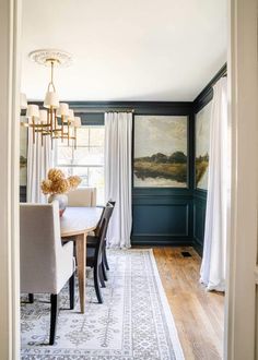 a dining room with green walls and white curtains