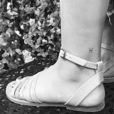 black and white photo of woman's foot with cross tattoo on her left ankle