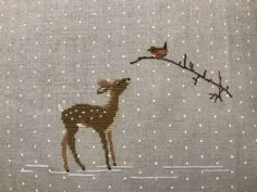 a cross stitched picture of a deer in the snow with a bird on it's back