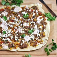 a pizza sitting on top of a cutting board covered in cheese and toppings next to tomatoes