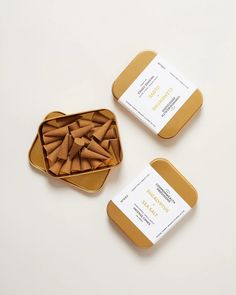 two tins filled with wooden dowks sitting on top of a white table next to each other