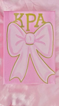 a pink napkin with a large bow on it's front and the word kpa written in gold