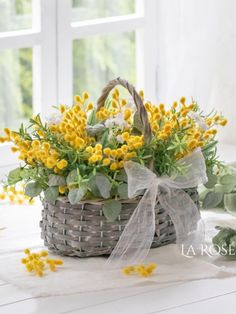 a basket filled with yellow flowers sitting on top of a white table next to a window