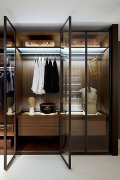 a walk in closet with clothes hanging on the shelves and other items sitting on top of it