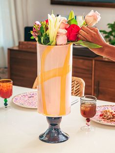 a vase filled with flowers sitting on top of a table next to plates and glasses