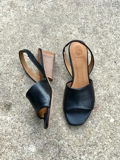 Black Mules With Wooden Low Heel, Black Sandals With Wooden Low Heel, Black Slingback Sandals With Padded Heel, Black Leather Block Heels With Wooden Heel, Black Mules With Low Heel And Heel Loop, Chic Black Slingback Sandals With Wooden Heel, Black Low Heel Slingback Sandals With Sculpted Heel, Black Slingback Sandals With Wooden Heel, Black Low Heel Slingback Pumps With Heel Loop