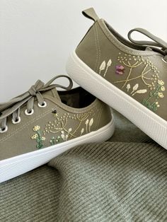 a pair of green shoes with embroidered flowers on them