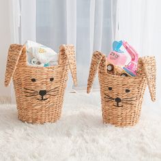 two wicker baskets with animals on them sitting on a fluffy white rug in front of a window