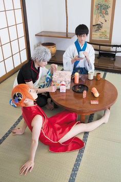 two people sitting at a table with food and drinks in front of them on the floor