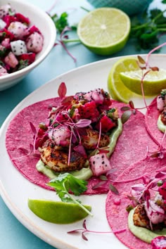 three tacos on a plate with limes and radishes