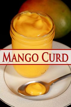 mango curd in a glass jar on a plate with a spoon next to it