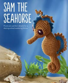 a crocheted sea horse is in the sand with shells and starfish around it