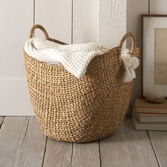 a large woven basket sitting on top of a wooden floor next to a framed photo