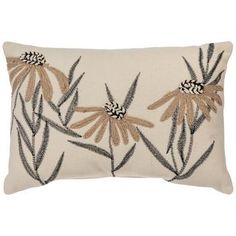 a white pillow with black and tan flowers on it's side, in front of a