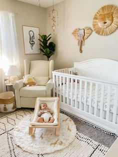 a baby laying in a crib next to a white chair and table with a potted plant on it