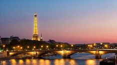 the eiffel tower is lit up at night over the river seine in paris