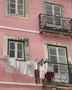 clothes hanging out to dry on a balcony in front of a pink building with two balconies