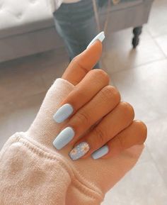 a woman's hand with blue nail polish and white flowers on it, holding onto her arm