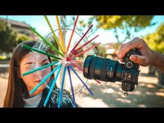 a woman holding a camera taking a photo with colored sticks in front of her face