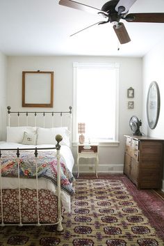 a bed room with a neatly made bed and a ceiling fan