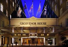 the exterior of a large hotel with flags on it's front and windows lit up at night