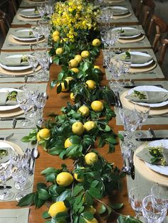 a long table is set with lemons and greenery for a festive dinner