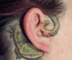 an ear with a lizard tattoo on it