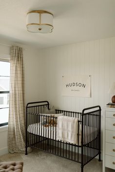 a baby's crib in the corner of a room with white walls and curtains