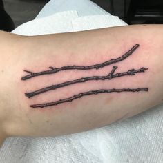 a branch tattoo on the left arm is shown in black and grey ink, with three branches sticking out of it